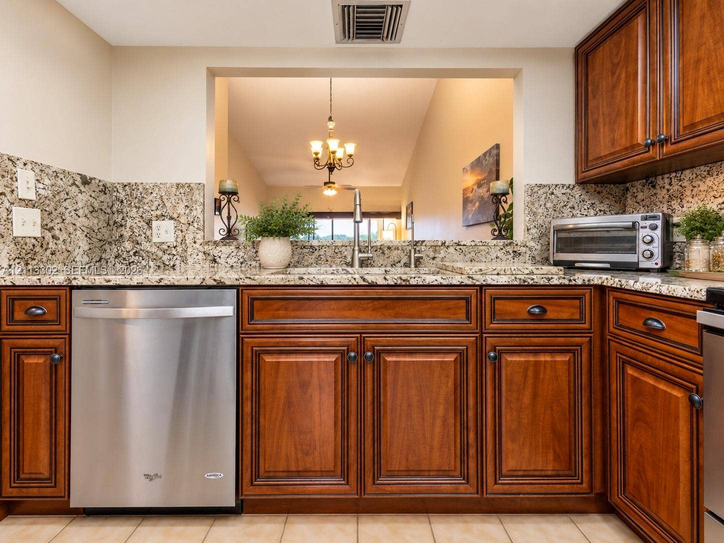 9450 Meadowood Drive, #202, Fort Pierce, FL 34951 Kitchen featuring natural stone countertops, tile backsplash, warm-toned wooden cabinetry, and stainless steel dishwasher