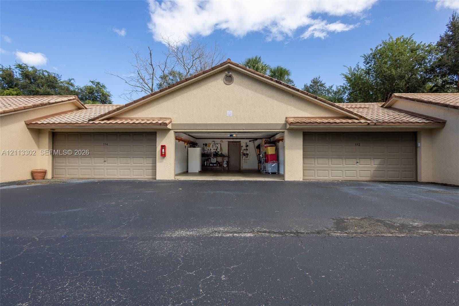 9450 Meadowood Drive, #202, Fort Pierce, FL 34951 Multi-bay garage exterior featuring stucco siding, tile roofing, and paved driveway space