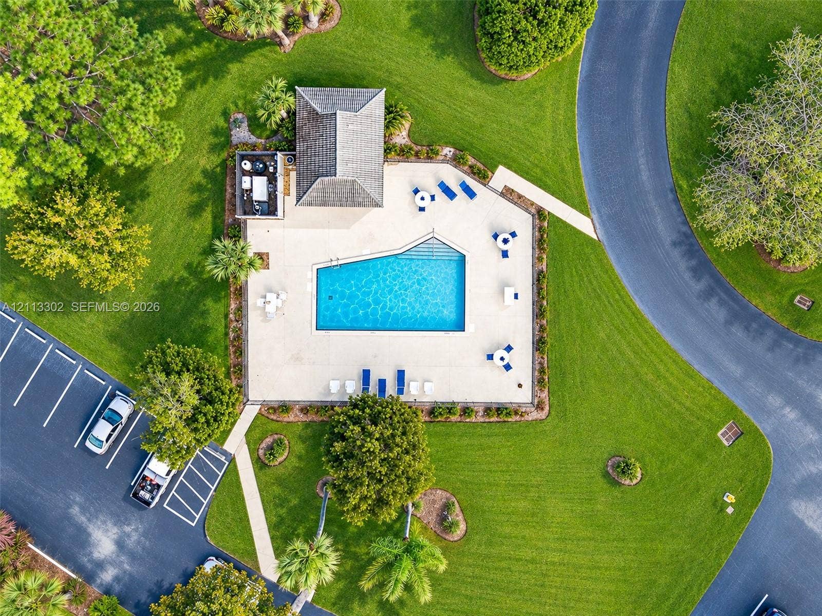 9450 Meadowood Drive, #202, Fort Pierce, FL 34951 Swimming pool with an expansive concrete deck, shaded structure, and manicured surrounding grounds