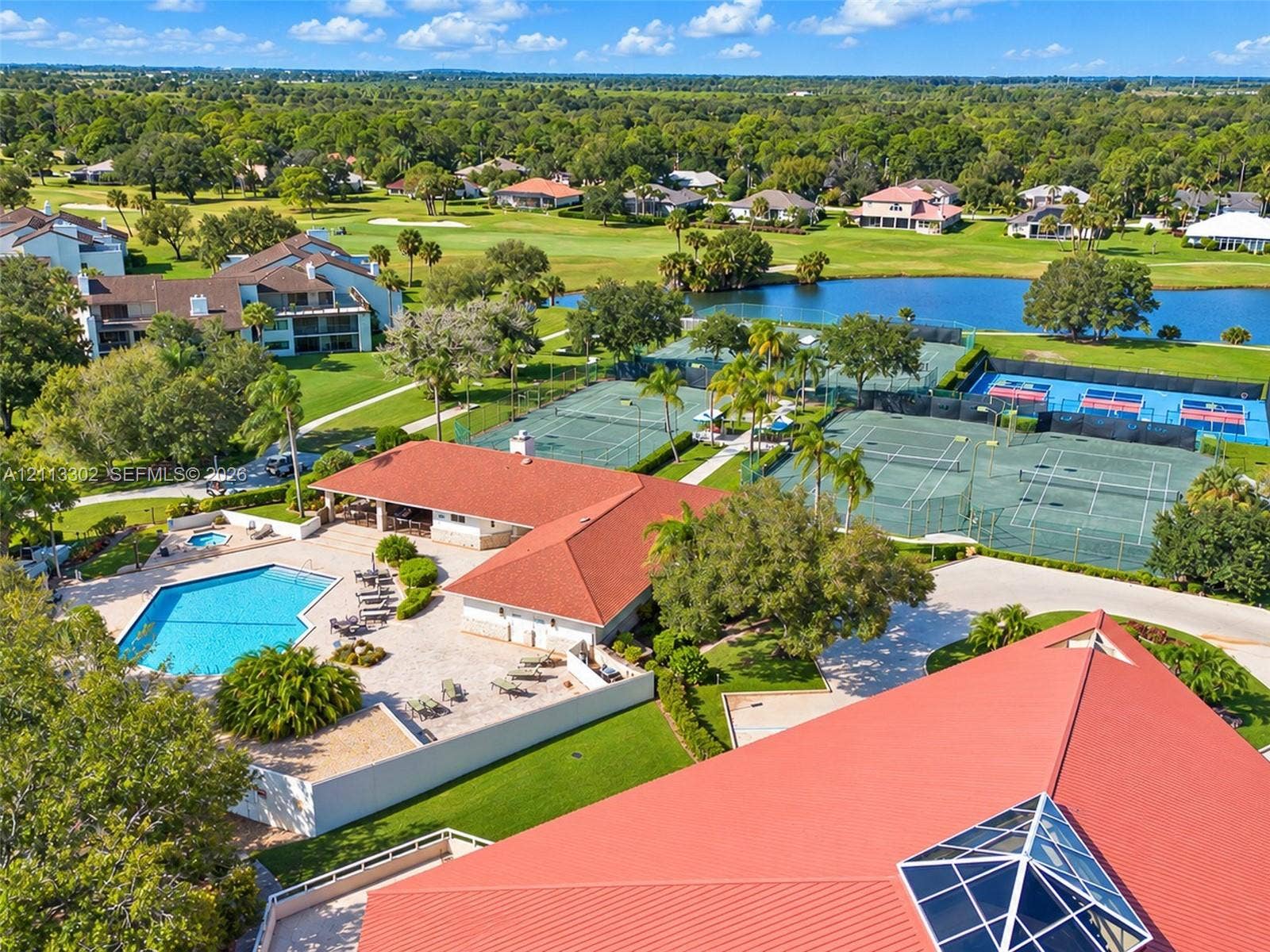 9450 Meadowood Drive, #202, Fort Pierce, FL 34951 Recreational complex featuring multiple tennis courts, a swimming pool, an integrated spa, and a pavilion with a red metal roof