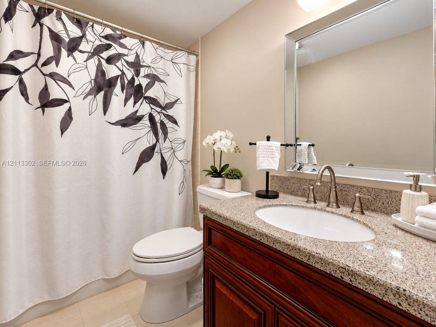 9450 Meadowood Drive, #202, Fort Pierce, FL 34951 Bathroom vanity featuring a stone-composite countertop, undermount sink, gooseneck faucet, wooden cabinetry, and a large rectangular mirror with a beveled frame
