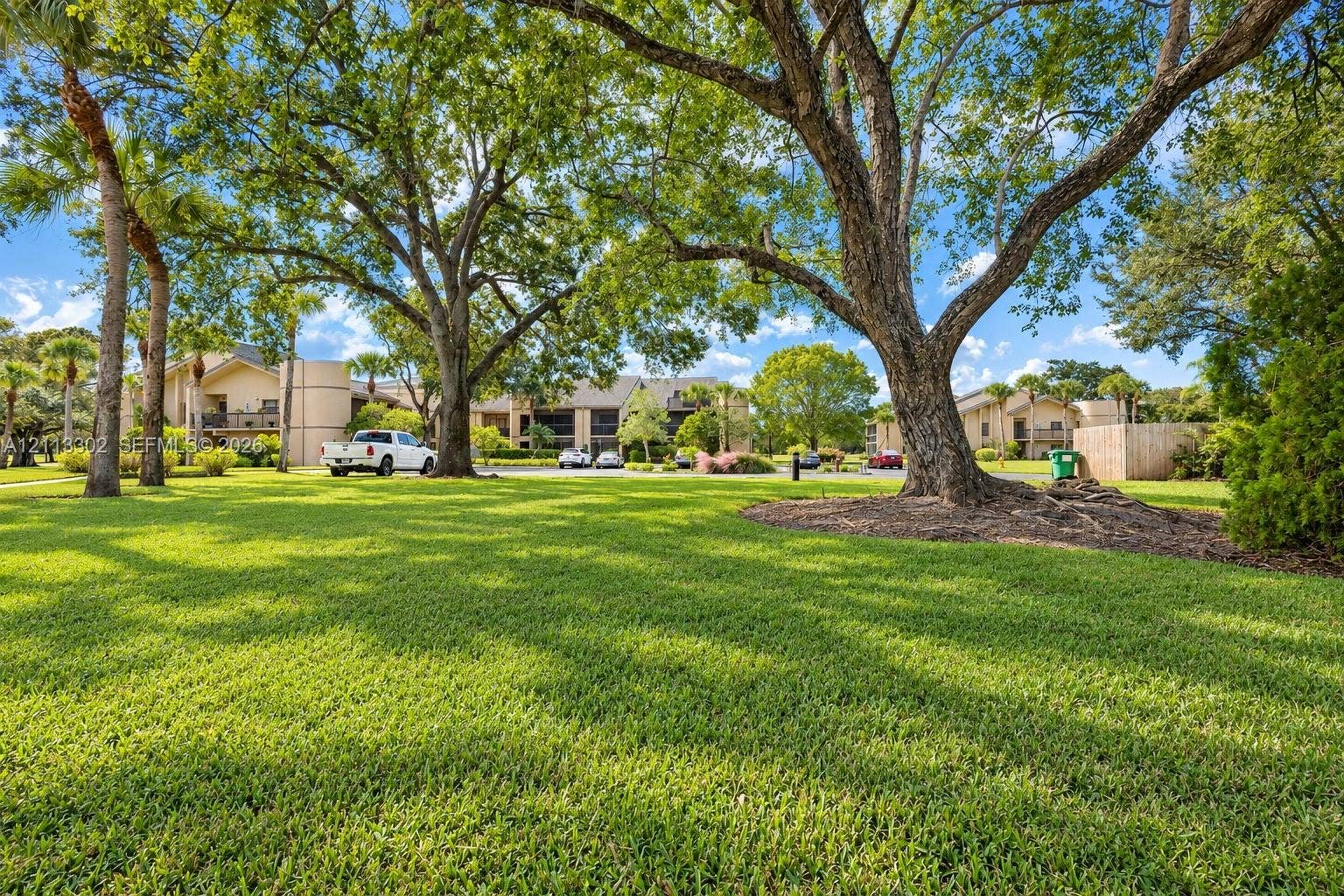 9450 Meadowood Drive, #202, Fort Pierce, FL 34951 Expansive lawn area featuring mature hardwood trees and palm trees