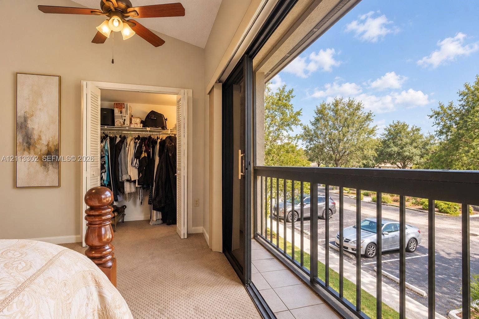 9450 Meadowood Drive, #202, Fort Pierce, FL 34951 Vaulted ceiling with a central multi-blade ceiling fan, sliding glass doors, and a tiled balcony featuring black metal railings