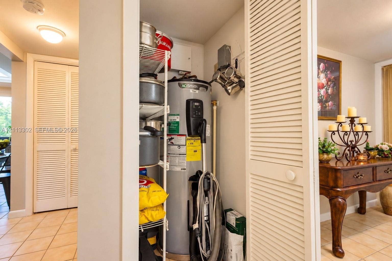 9450 Meadowood Drive, #202, Fort Pierce, FL 34951 Utility closet featuring louvered bi-fold doors, white wire shelving, and a water heater