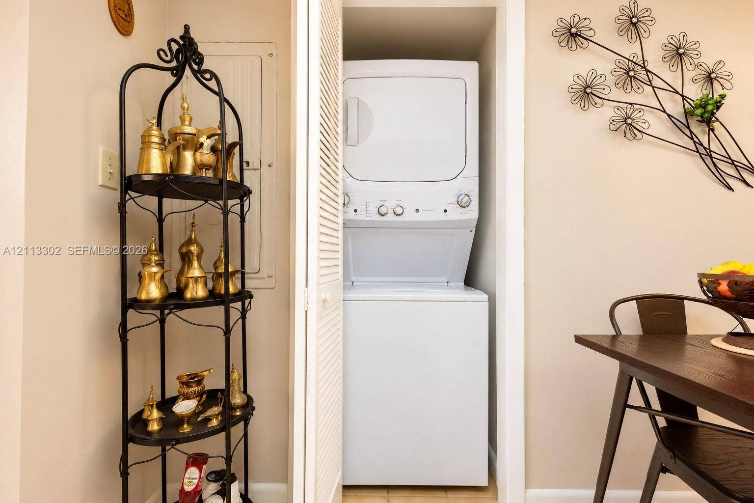 9450 Meadowood Drive, #202, Fort Pierce, FL 34951 Laundry area featuring a stacked washer and dryer unit concealed by louvered bi-fold doors
