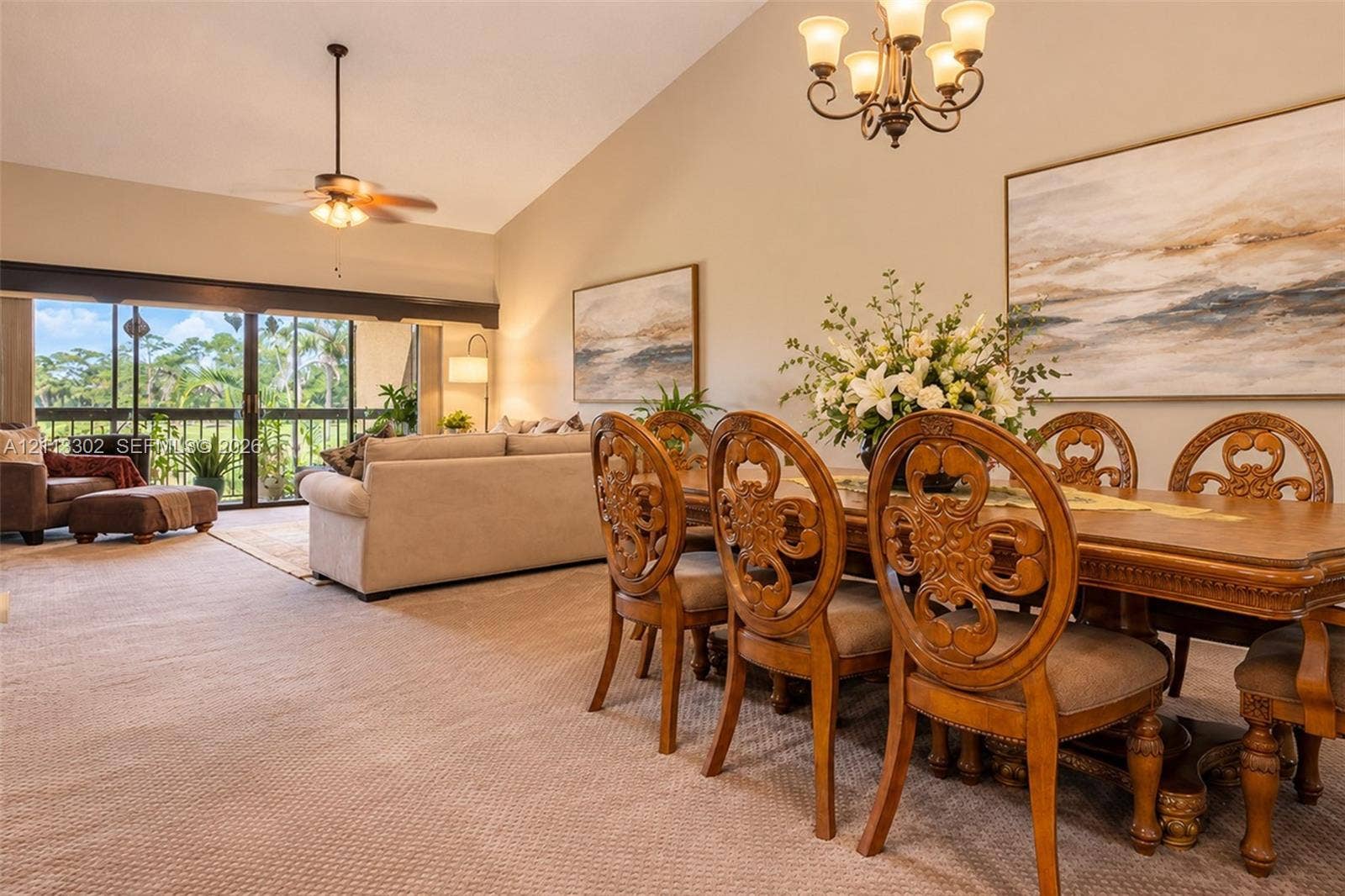 9450 Meadowood Drive, #202, Fort Pierce, FL 34951 Vaulted ceilings, expansive glass sliding doors, integrated ceiling fan, and traditional multi-arm chandelier