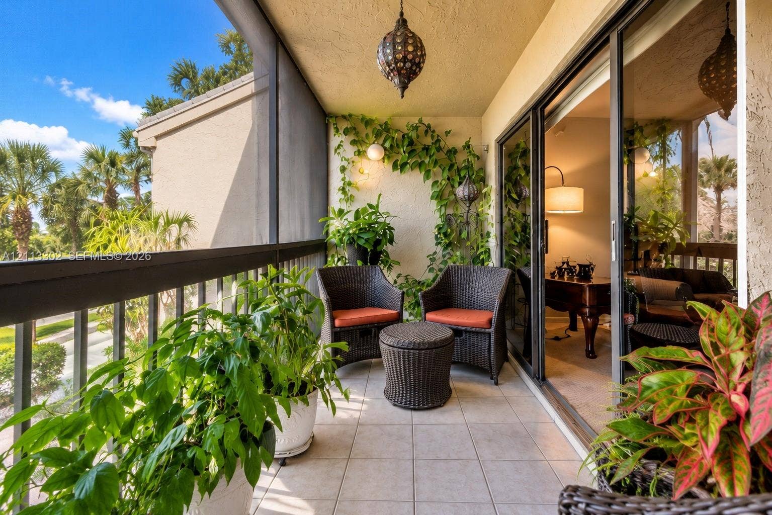 9450 Meadowood Drive, #202, Fort Pierce, FL 34951 Screened balcony featuring ceramic tile flooring, a decorative metal hanging pendant light, sliding glass entry doors, and a metal railing