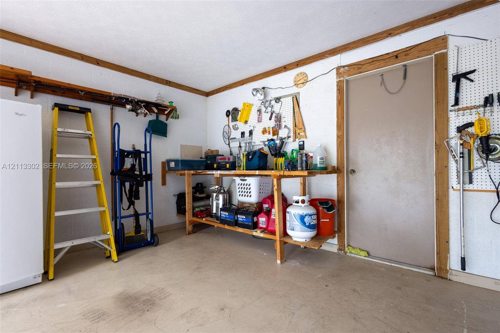 9450 Meadowood Drive, #202, Fort Pierce, FL 34951 Garage space featuring a built-in wooden workbench, wall-mounted pegboard organization, and wooden ceiling trim