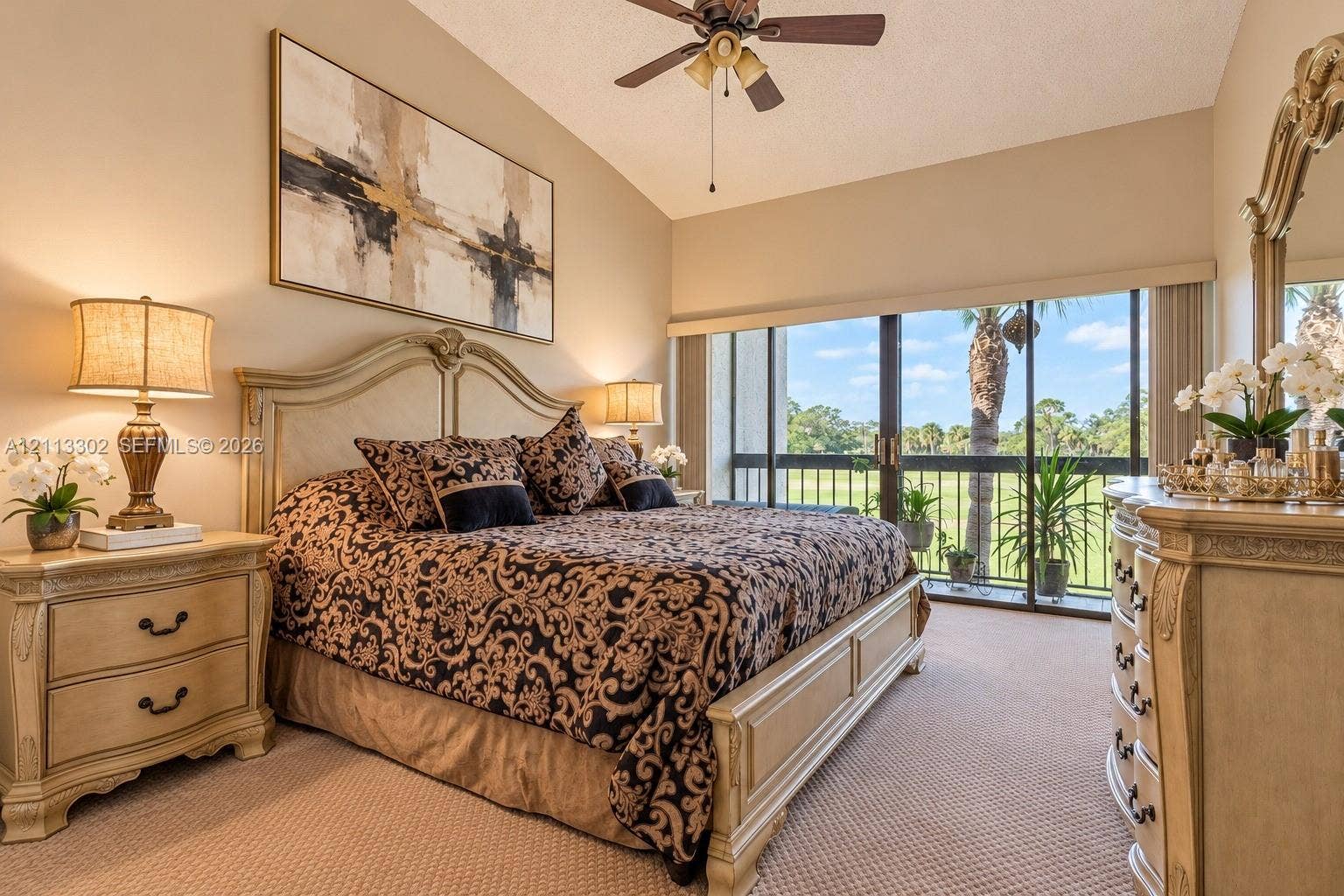 9450 Meadowood Drive, #202, Fort Pierce, FL 34951 Vaulted ceiling featuring a central lighted ceiling fan, wall-to-wall carpeting, and sliding glass doors with exterior balcony access