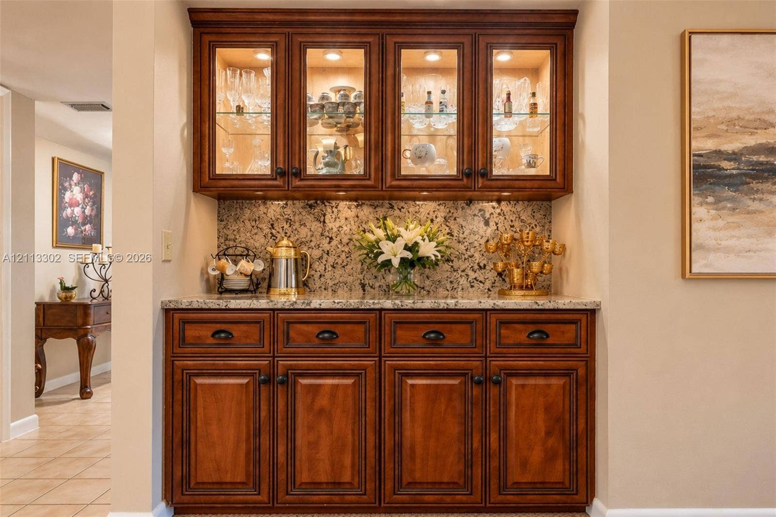 9450 Meadowood Drive, #202, Fort Pierce, FL 34951 Built-in cabinetry featuring rich-toned wood finish, stone-surfaced countertop, glass-front upper cabinet doors, and integrated cabinet lighting