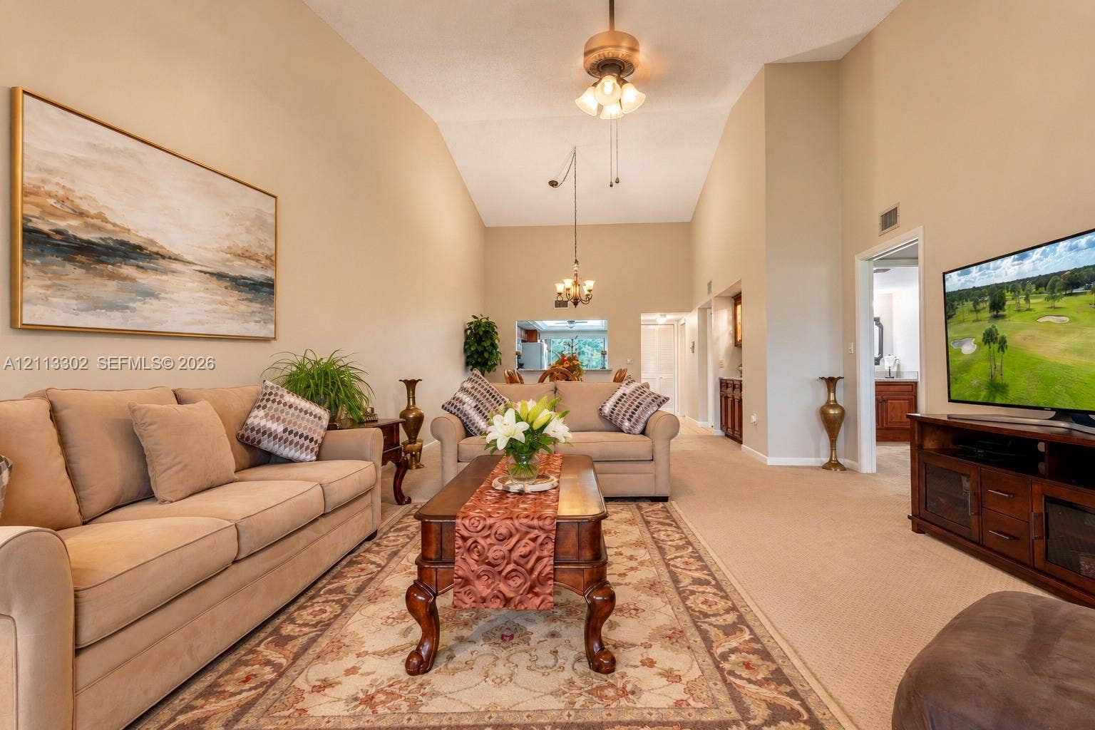 9450 Meadowood Drive, #202, Fort Pierce, FL 34951 Vaulted ceilings featuring a central ceiling fan and pendant lighting, with a passthrough opening to the kitchen area