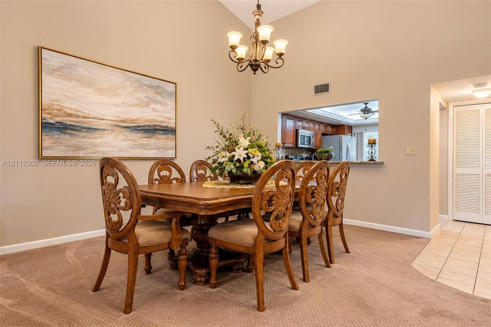 9450 Meadowood Drive, #202, Fort Pierce, FL 34951 Dining space featuring vaulted ceilings, a multi-arm chandelier, and a serving pass-through opening to the kitchen