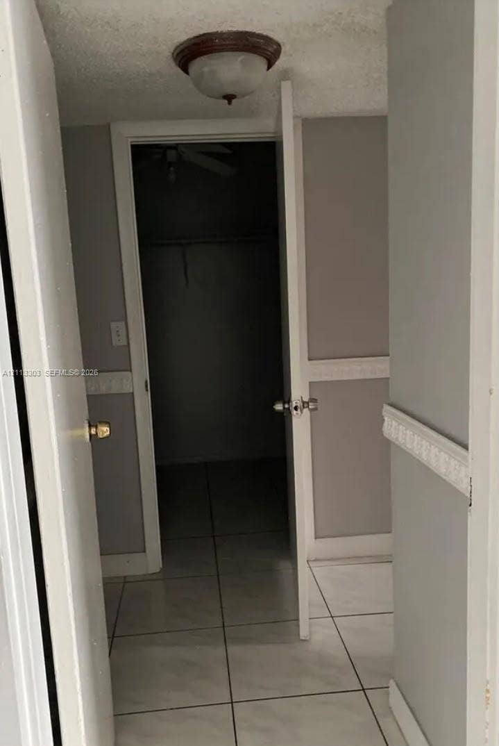 Lauderdale Lakes, FL 33313 Large-format tile flooring, walls featuring decorative chair rail molding, and a built-in closet with overhead lighting
