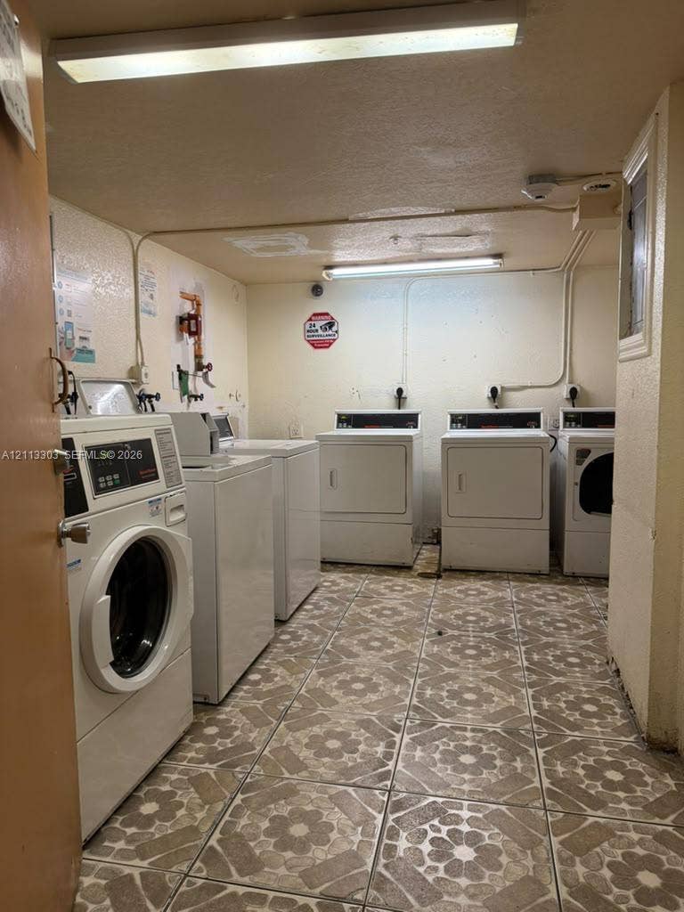 Lauderdale Lakes, FL 33313 Utility room featuring patterned ceramic tile flooring and multiple white industrial-grade laundry appliances