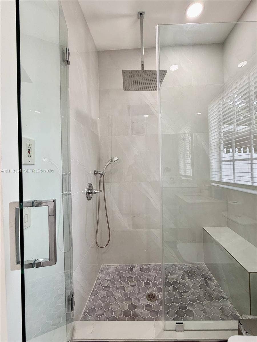 1810 SW 5th Avenue, #n/a, Miami, Miami, FL 33129 Walk-in shower featuring a frameless glass enclosure, ceiling-mounted rainfall showerhead, handheld sprayer, built-in bench, and grey hexagonal floor tile
