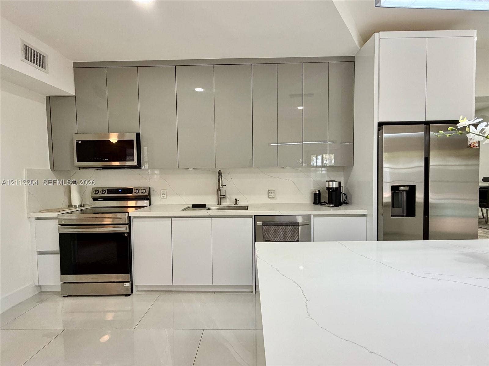 1810 SW 5th Avenue, #n/a, Miami, Miami, FL 33129 Kitchen featuring high-gloss cabinetry, stone-finish countertops with matching backsplash, stainless steel appliances, and large-format tile flooring