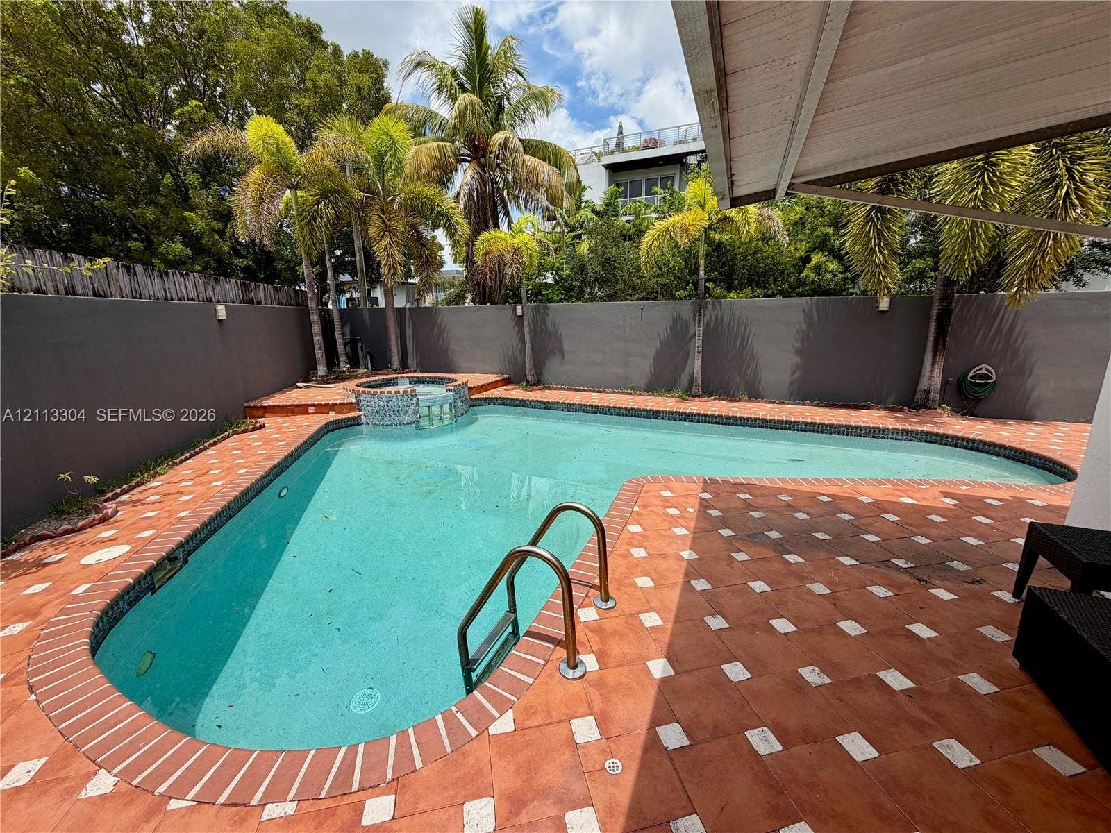 1810 SW 5th Avenue, #n/a, Miami, Miami, FL 33129 Backyard featuring an inground pool with tile coping, an attached spa, terra cotta paver hardscaping, perimeter masonry walls, and mature palm trees