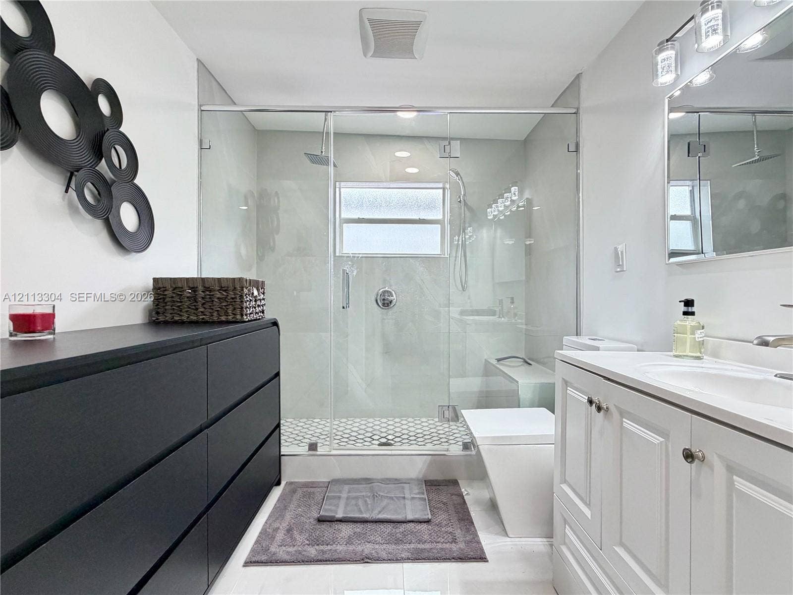 1810 SW 5th Avenue, #n/a, Miami, Miami, FL 33129 Walk-in shower with a glass enclosure, rainfall showerhead, and hexagonal tile flooring, paired with a white vanity featuring an integrated sink and chrome hardware