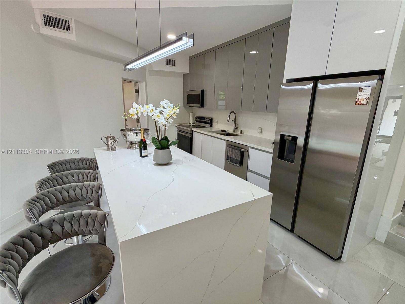 1810 SW 5th Avenue, #n/a, Miami, Miami, FL 33129 Kitchen featuring a waterfall-edge island with stone-finish countertop, high-gloss cabinetry, stainless steel appliances, and linear pendant lighting