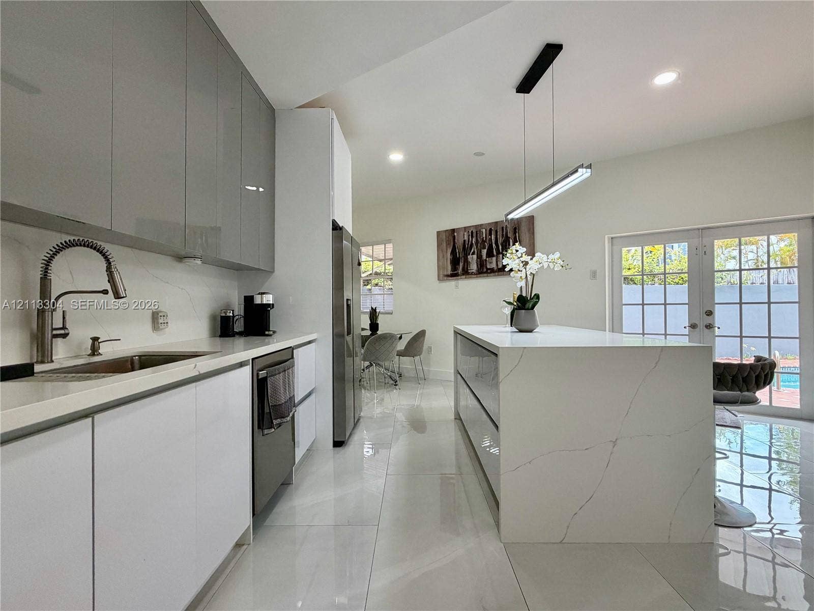 1810 SW 5th Avenue, #n/a, Miami, Miami, FL 33129 Modern kitchen featuring high-gloss cabinetry, a waterfall-edge stone island, polished tile flooring, and a linear pendant light fixture