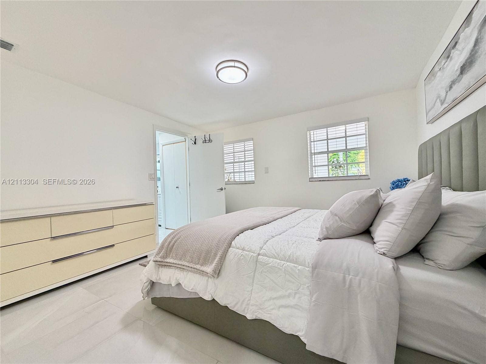 1810 SW 5th Avenue, #n/a, Miami, Miami, FL 33129 Neutral-toned interior featuring large-format tile flooring, dual-pane windows with horizontal blinds, and a circular flush-mount ceiling light fixture