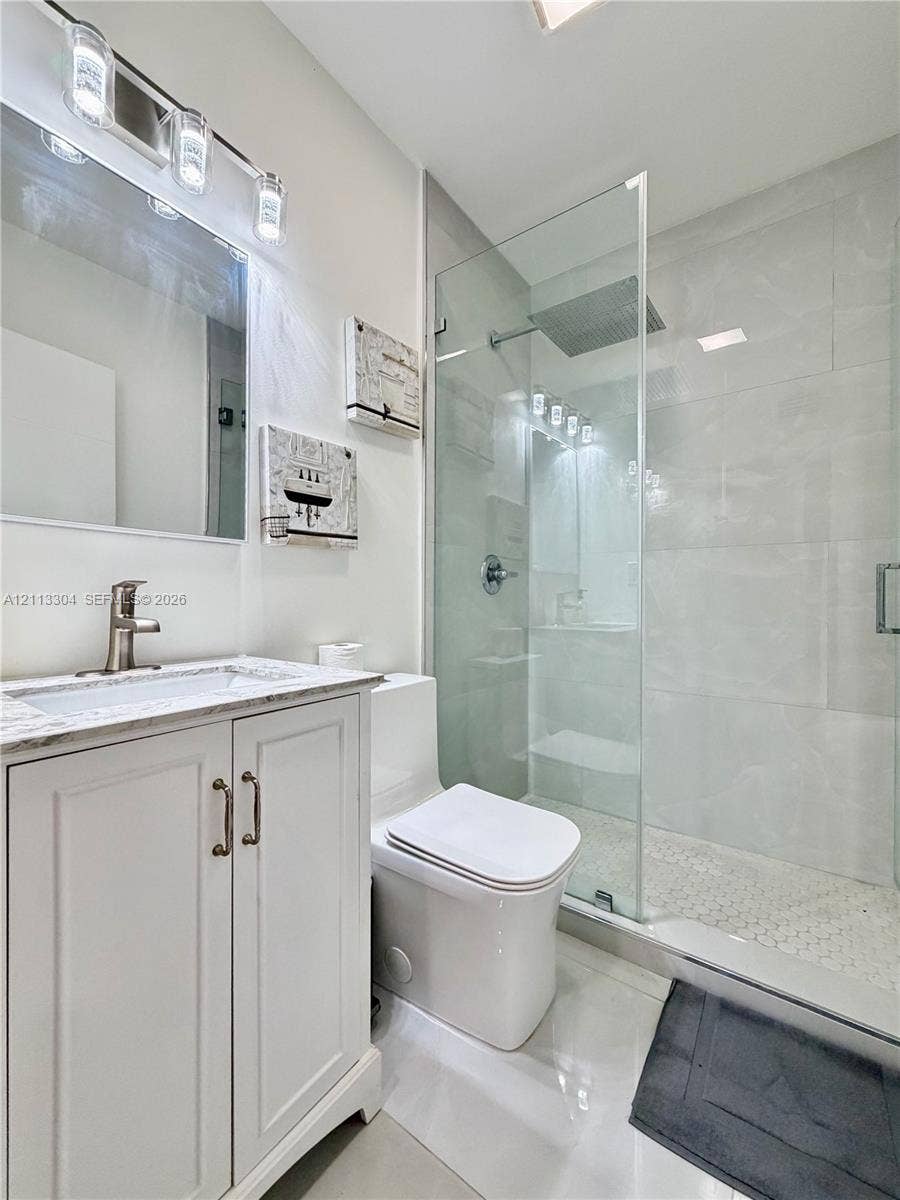 1810 SW 5th Avenue, #n/a, Miami, Miami, FL 33129 Bathroom featuring a white shaker-style vanity with a stone countertop, an integrated sink with a metallic faucet, a frameless glass-enclosed walk-in shower with tile walls, and a rainfall showerhead