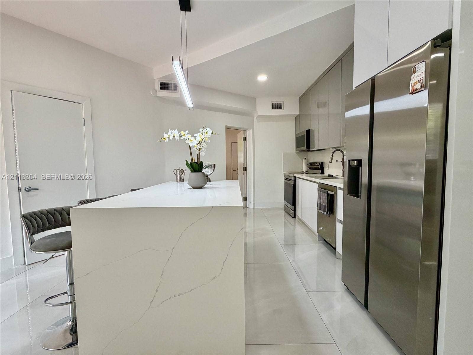 1810 SW 5th Avenue, #n/a, Miami, Miami, FL 33129 Kitchen featuring a waterfall-edge island with stone-finish countertop, high-gloss flat-panel cabinetry, stainless steel appliances, and large-format tile flooring