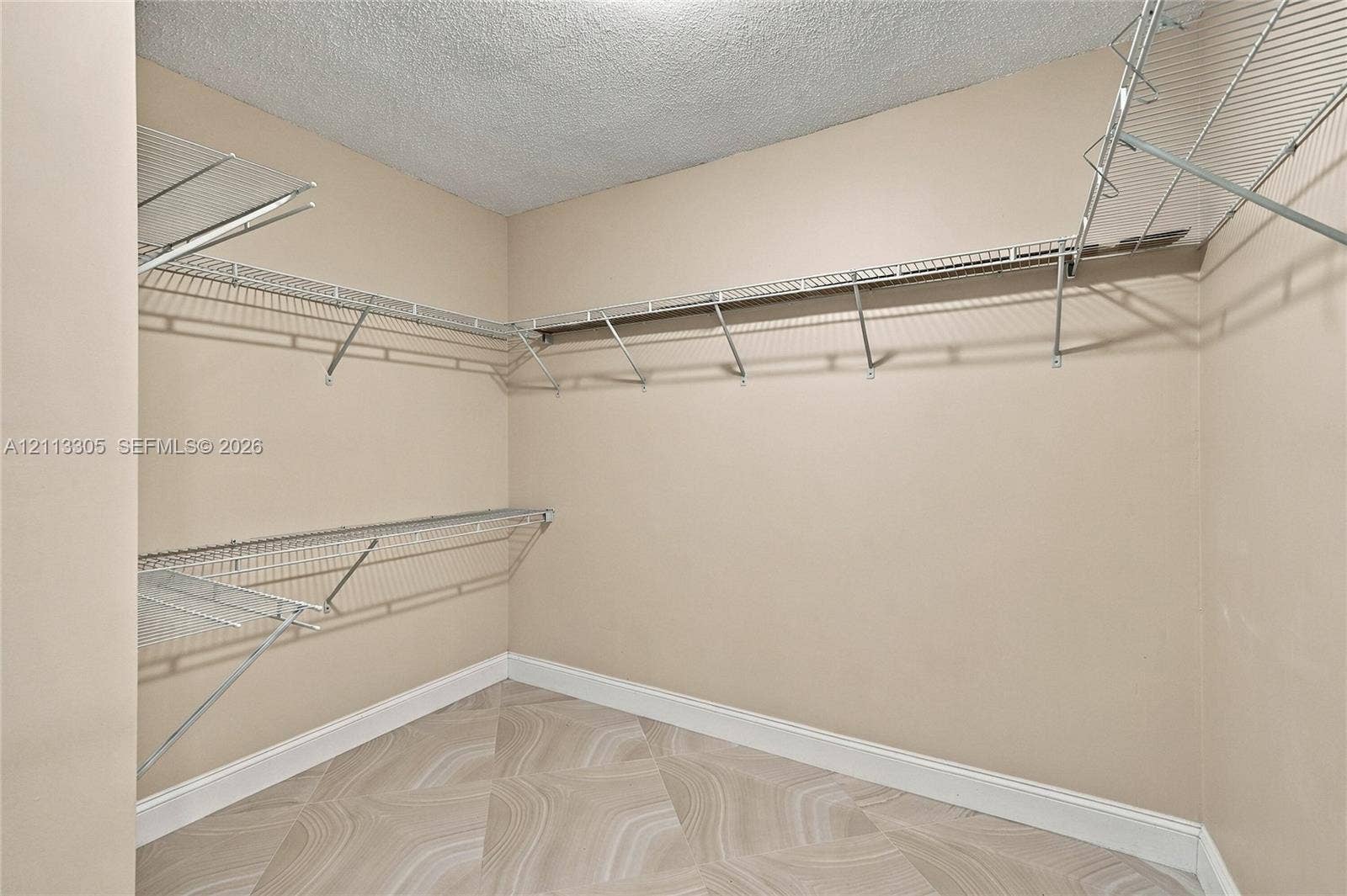 Walk-in closet featuring multi-level wire shelving and patterned tile flooring