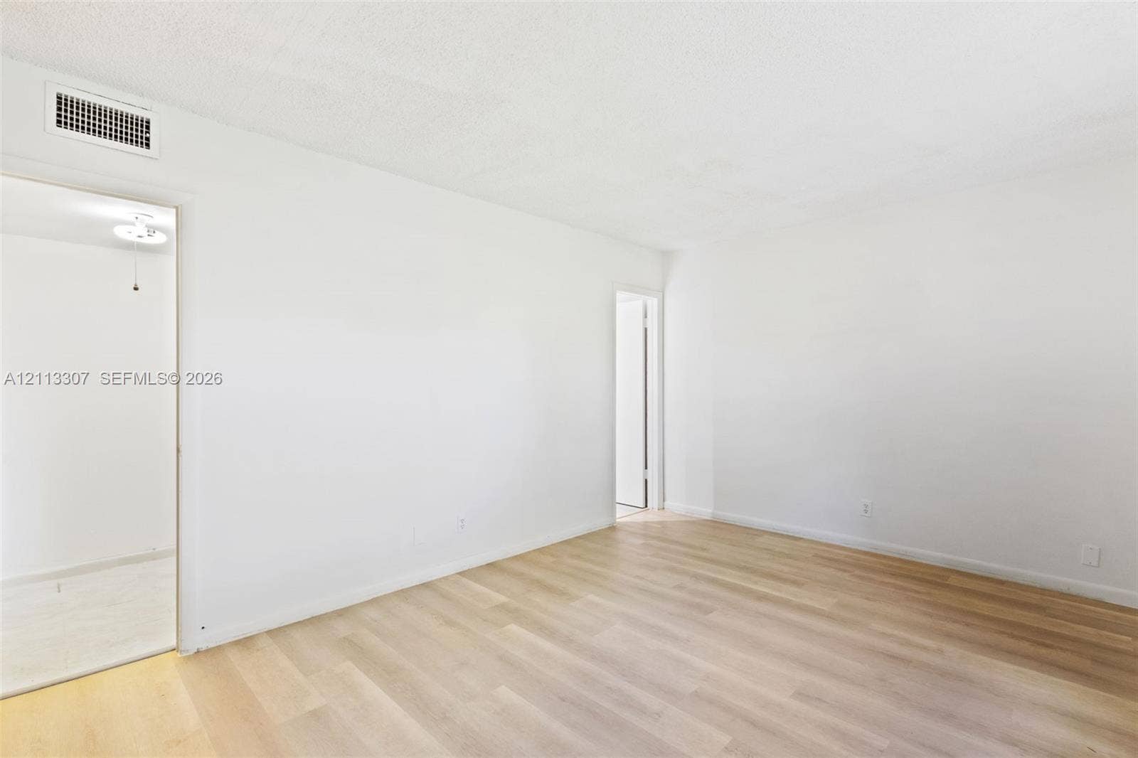 7605 NW 5th Place, #103, Margate, Margate, FL 33063 Neutral-toned living space featuring light wood-finish flooring and smooth, monochromatic walls
