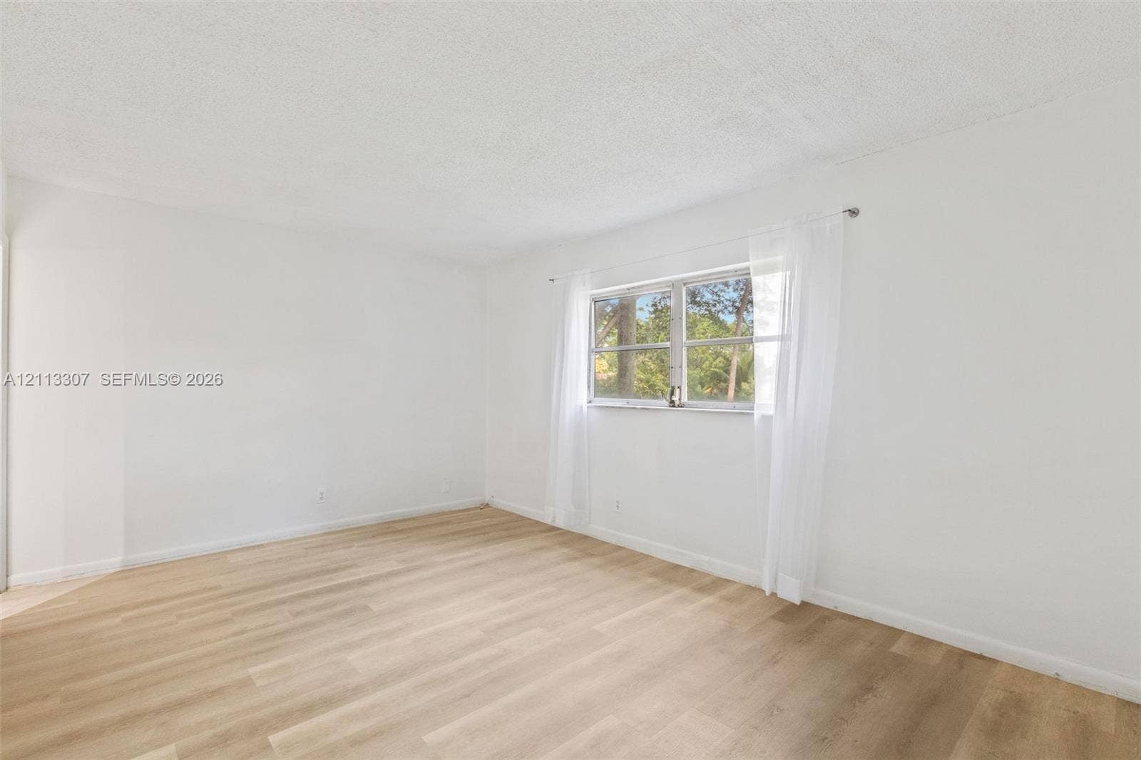 7605 NW 5th Place, #103, Margate, Margate, FL 33063 Interior room featuring wood-finish flooring, white walls, and a multi-pane window