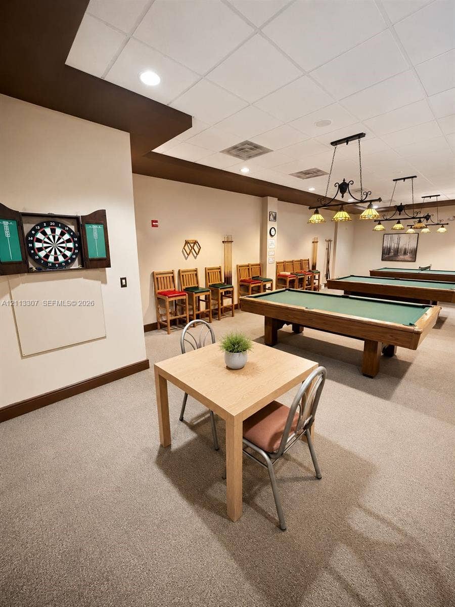 7605 NW 5th Place, #103, Margate, Margate, FL 33063 Recreation area featuring wall-mounted cabinetry, integrated billiard lighting fixtures, and a neutral carpeted floor