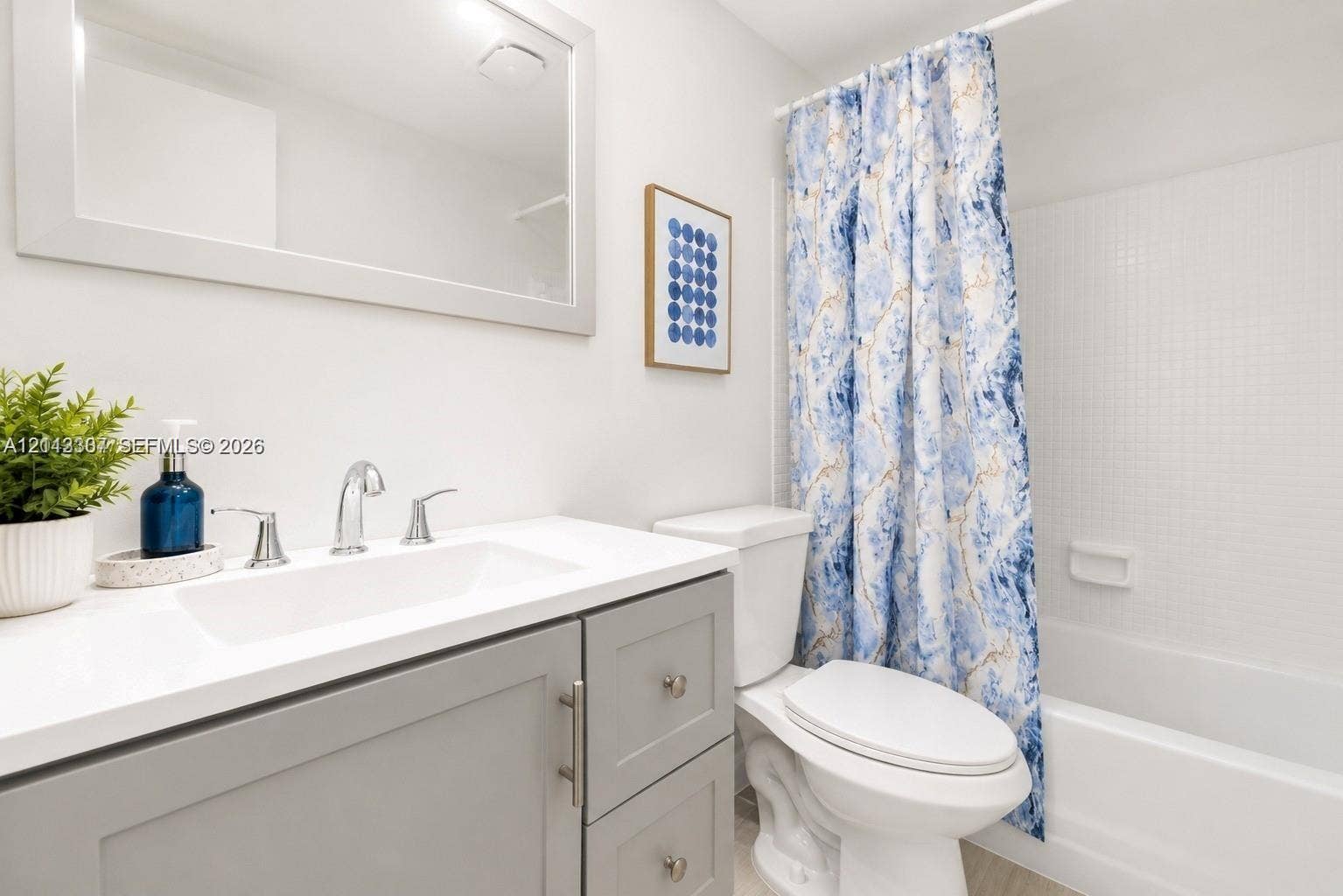 7605 NW 5th Place, #103, Margate, Margate, FL 33063 Bathroom featuring a grey shaker-style vanity, white countertop with an integrated sink, polished chrome faucet, framed wall mirror, and a tub-shower combination with white tiled surround
