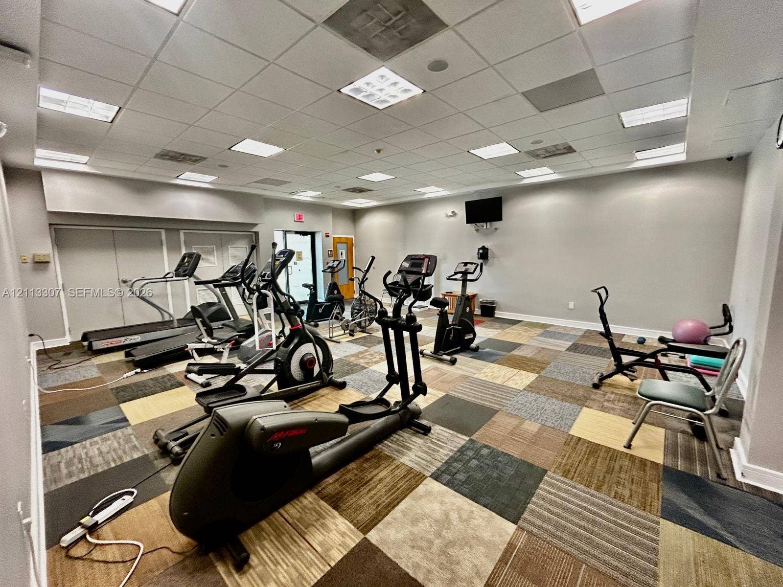 7605 NW 5th Place, #103, Margate, Margate, FL 33063 Fitness center featuring suspended grid ceiling, recessed panel lighting, and multi-toned modular carpet tiles