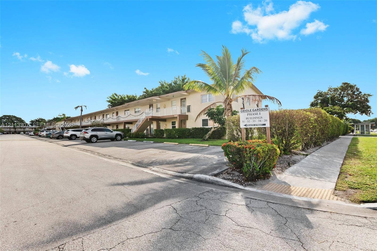 7605 NW 5th Place, #103, Margate, Margate, FL 33063 Exterior facade featuring stucco siding, multi-level building design, dedicated parking areas, concrete sidewalks, and mature landscaping