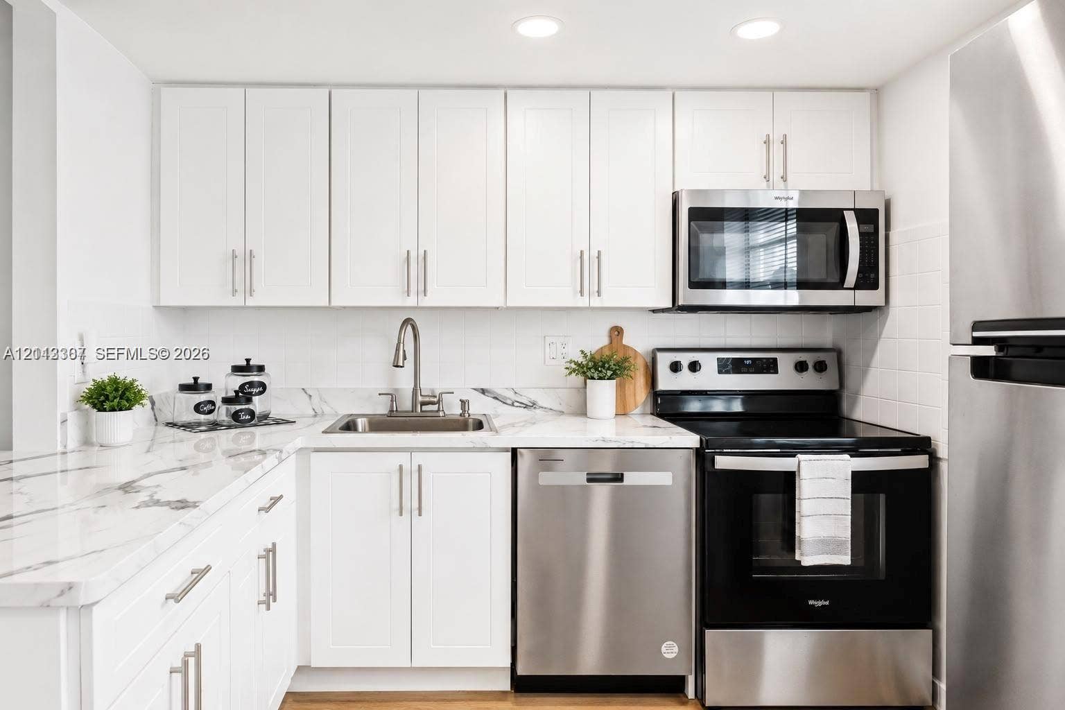 7605 NW 5th Place, #103, Margate, Margate, FL 33063 Kitchen featuring white shaker-style cabinetry, stone-patterned countertops, a white tile backsplash, stainless steel appliances, and recessed lighting