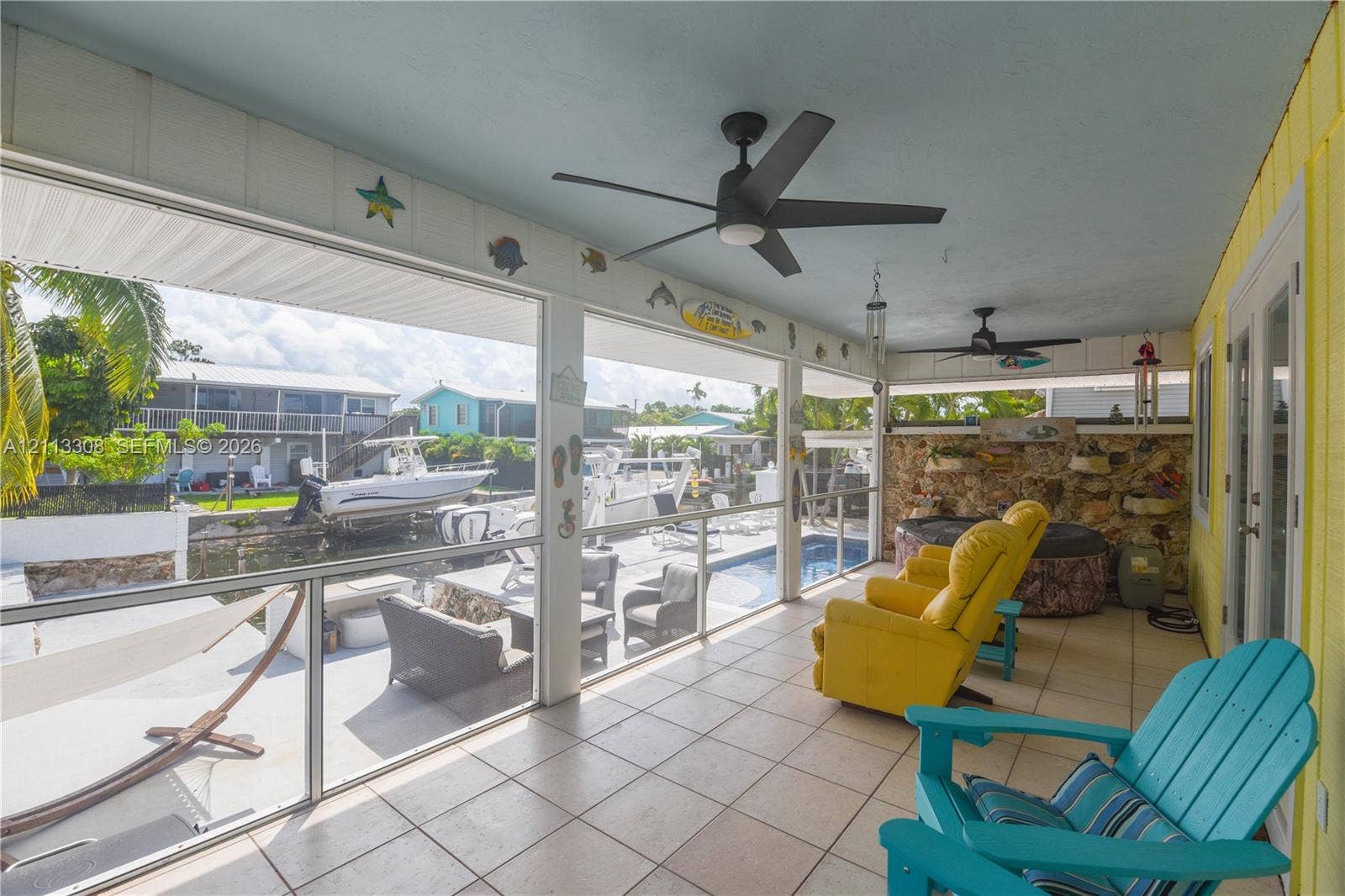 Screened-in porch featuring tile flooring, ceiling fans, and a stone accent wall
