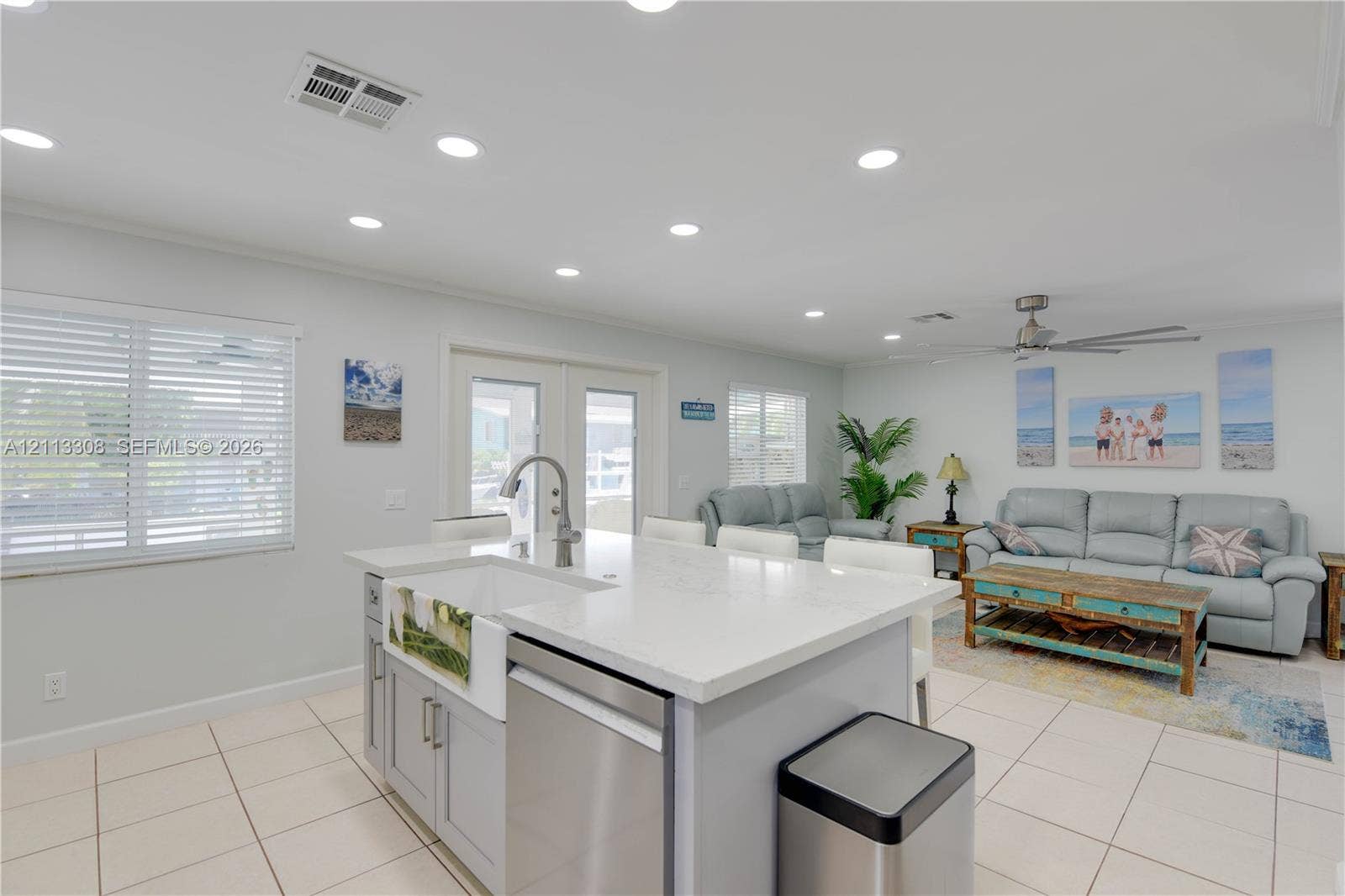 Kitchen island featuring a farmhouse-style sink, quartz countertops, stainless steel dishwasher, recessed ceiling lighting, and tile flooring
