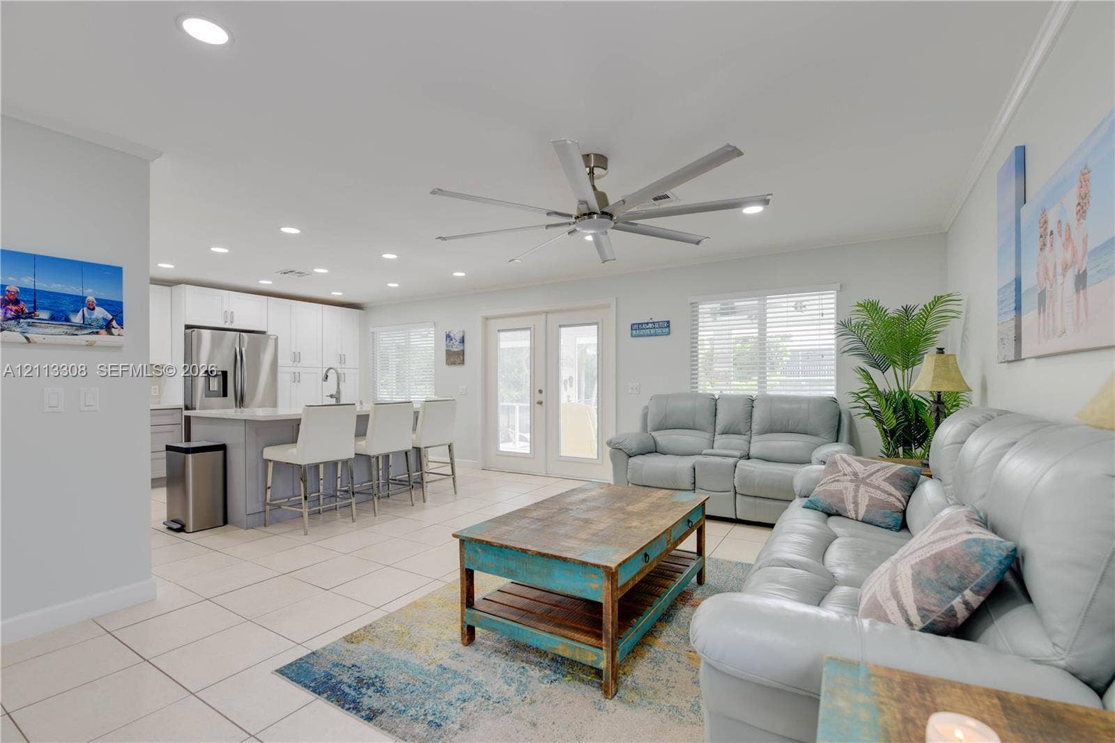 Open-concept kitchen featuring white shaker-style cabinetry, an island with seating, stainless steel appliances, recessed lighting, and tile flooring