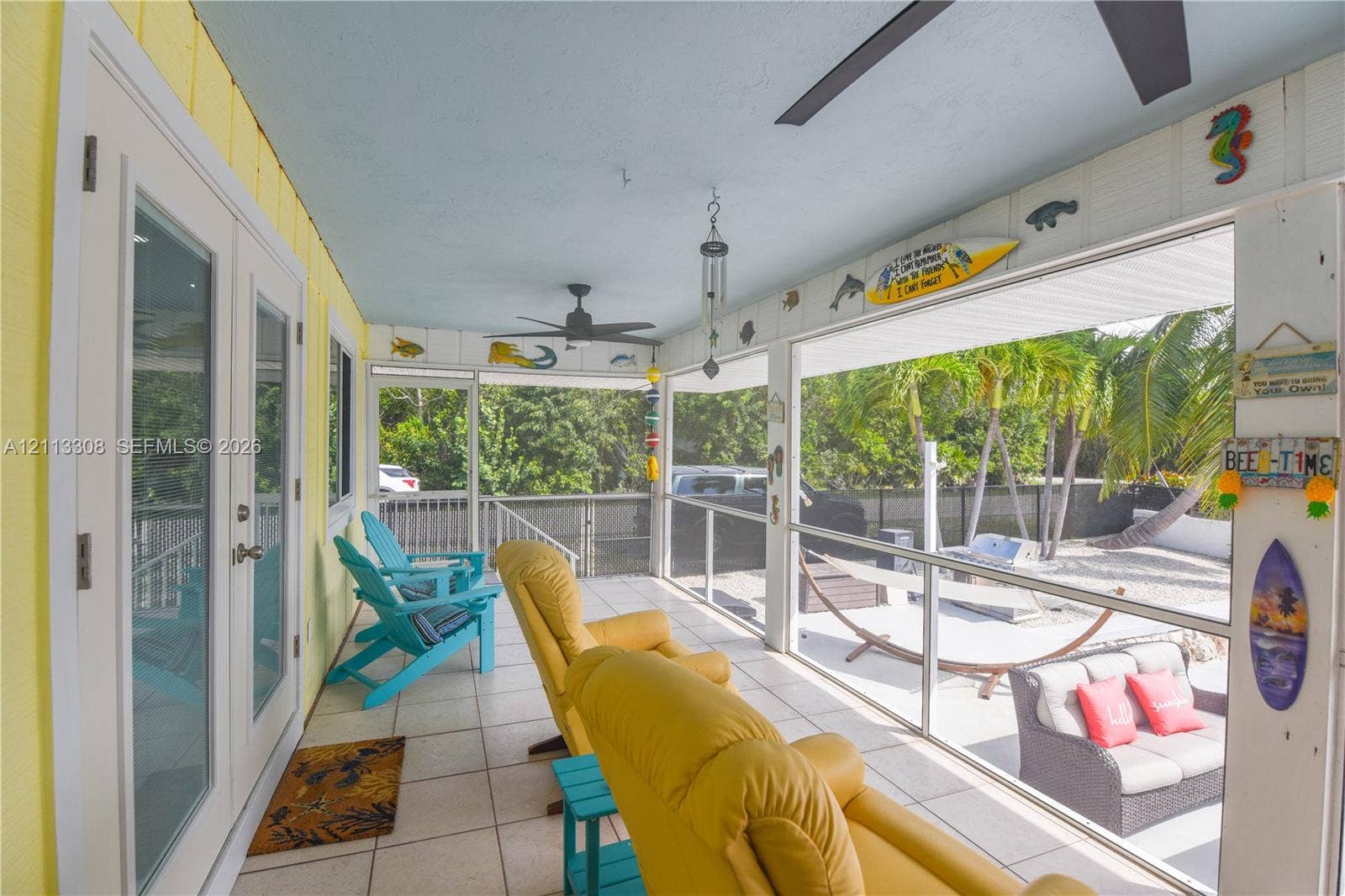 Screened-in porch featuring tile flooring, ceiling fans, and French doors
