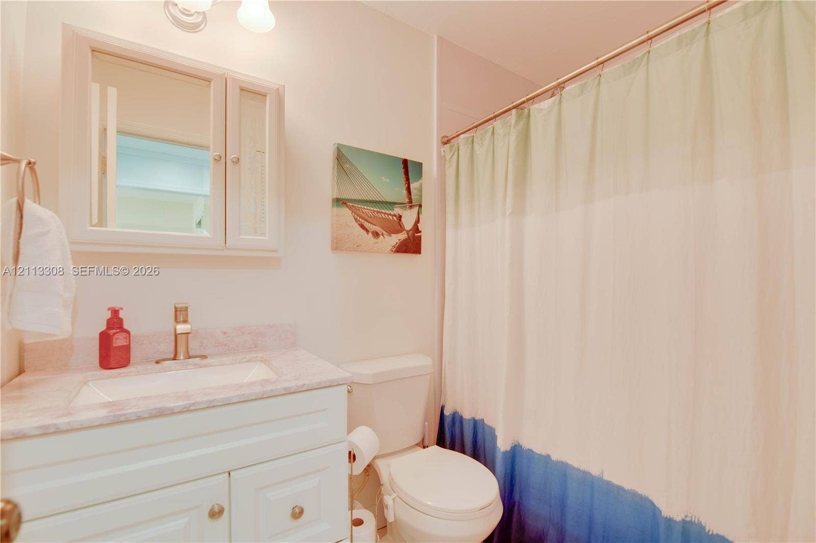 White vanity featuring a stone-composite countertop, rectangular drop-in sink, metallic faucet, wall-mounted medicine cabinet with integrated mirror, and dual-light fixture