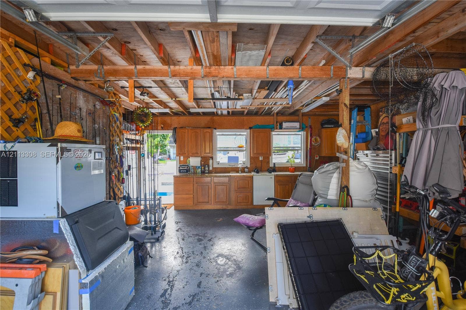 Garage space featuring wood-finish cabinetry, countertop workspace, and exposed beam ceiling structure