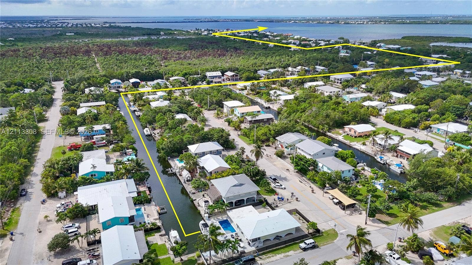 Aerial perspective of waterfront property featuring canal access, mature native vegetation, and coastal surroundings