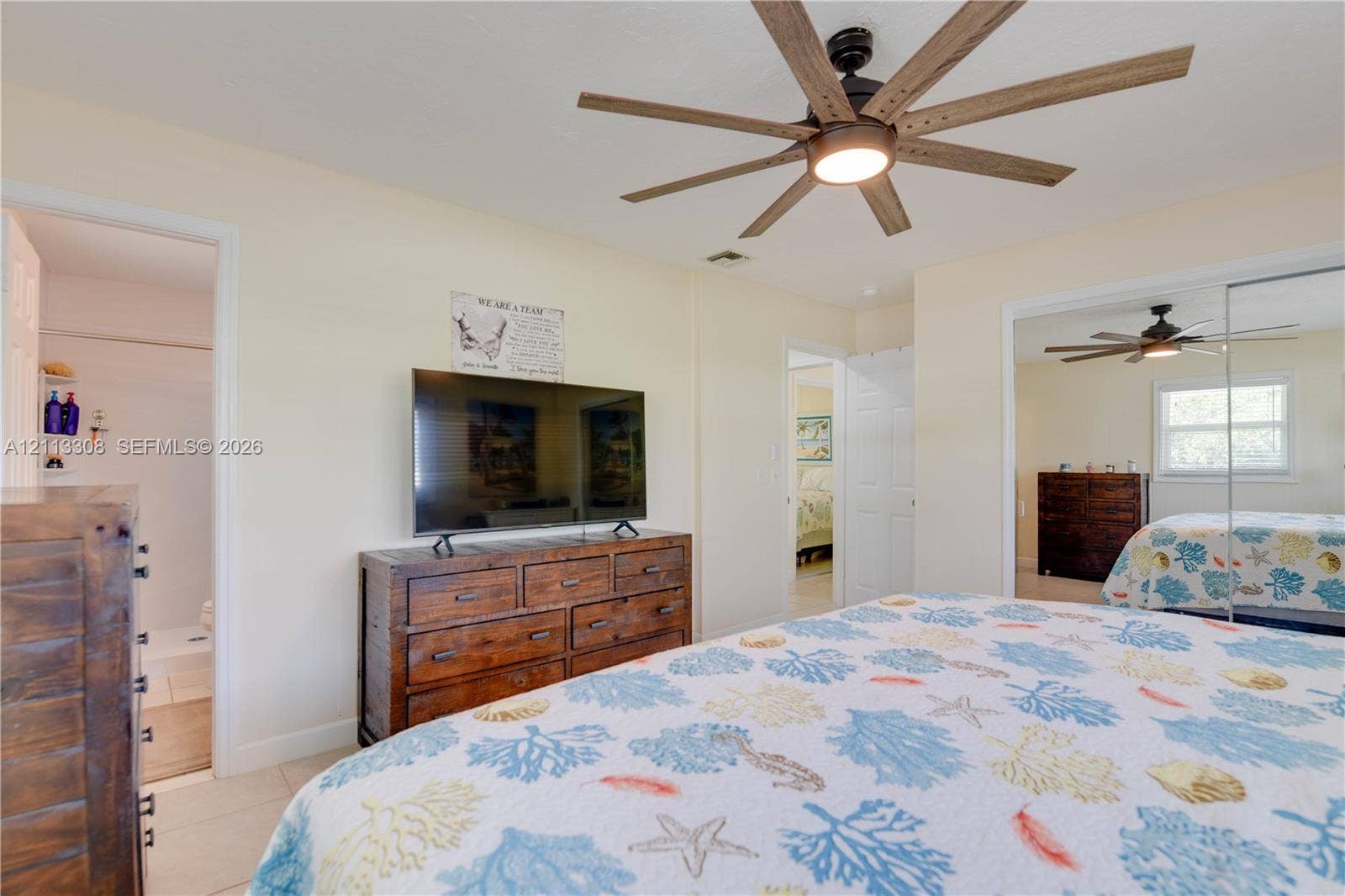 Modern ceiling fan with wood-finish blades, central light fixture, and mirrored sliding closet doors