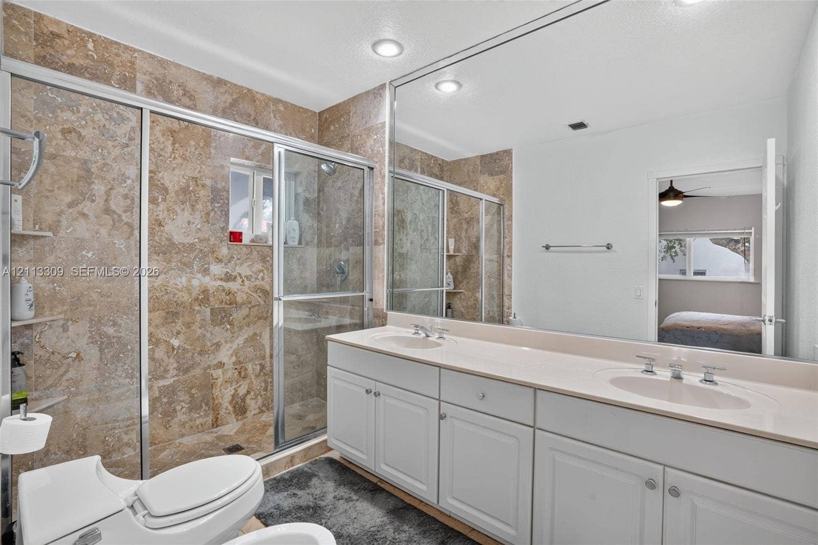 3082 Bird Avenue, #6, Miami, FL 33133 Dual-sink vanity with a solid-surface countertop, floor-to-ceiling framed mirror, and a walk-in shower featuring tile surrounds and a glass enclosure
