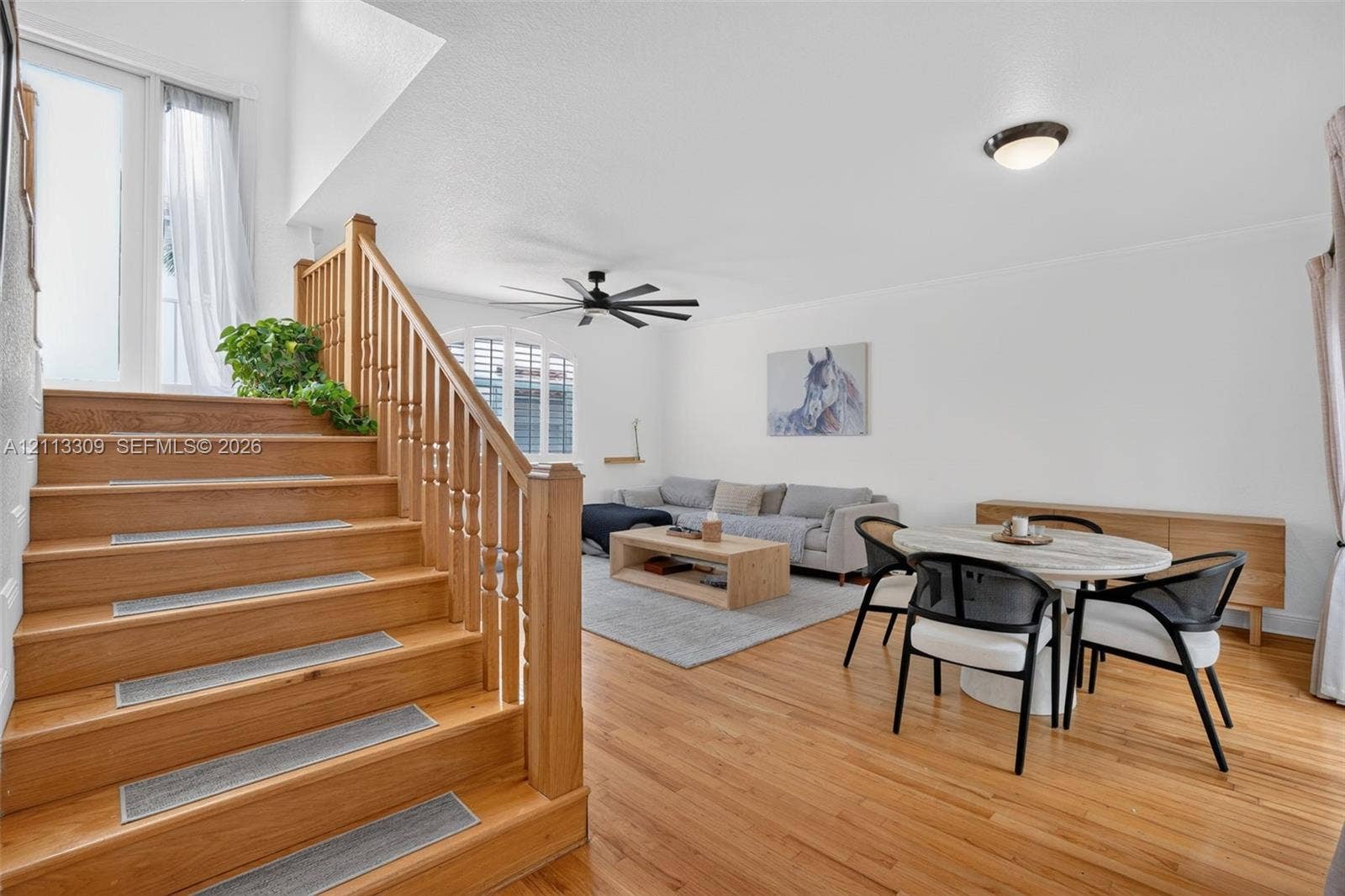 3082 Bird Avenue, #6, Miami, FL 33133 Wood-finish flooring, staircase with a wood balustrade and handrail, vaulted ceiling, and an arched window