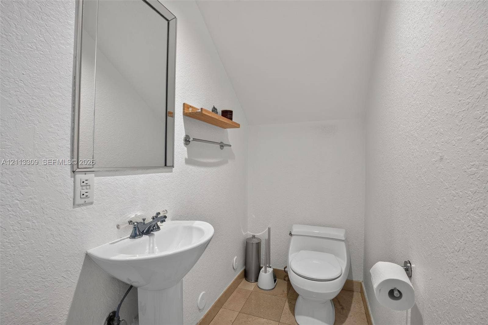 3082 Bird Avenue, #6, Miami, FL 33133 Pedestal sink with dual-handle chrome faucet, wall-mounted rectangular mirror, wood-finish wall shelving, and tile flooring