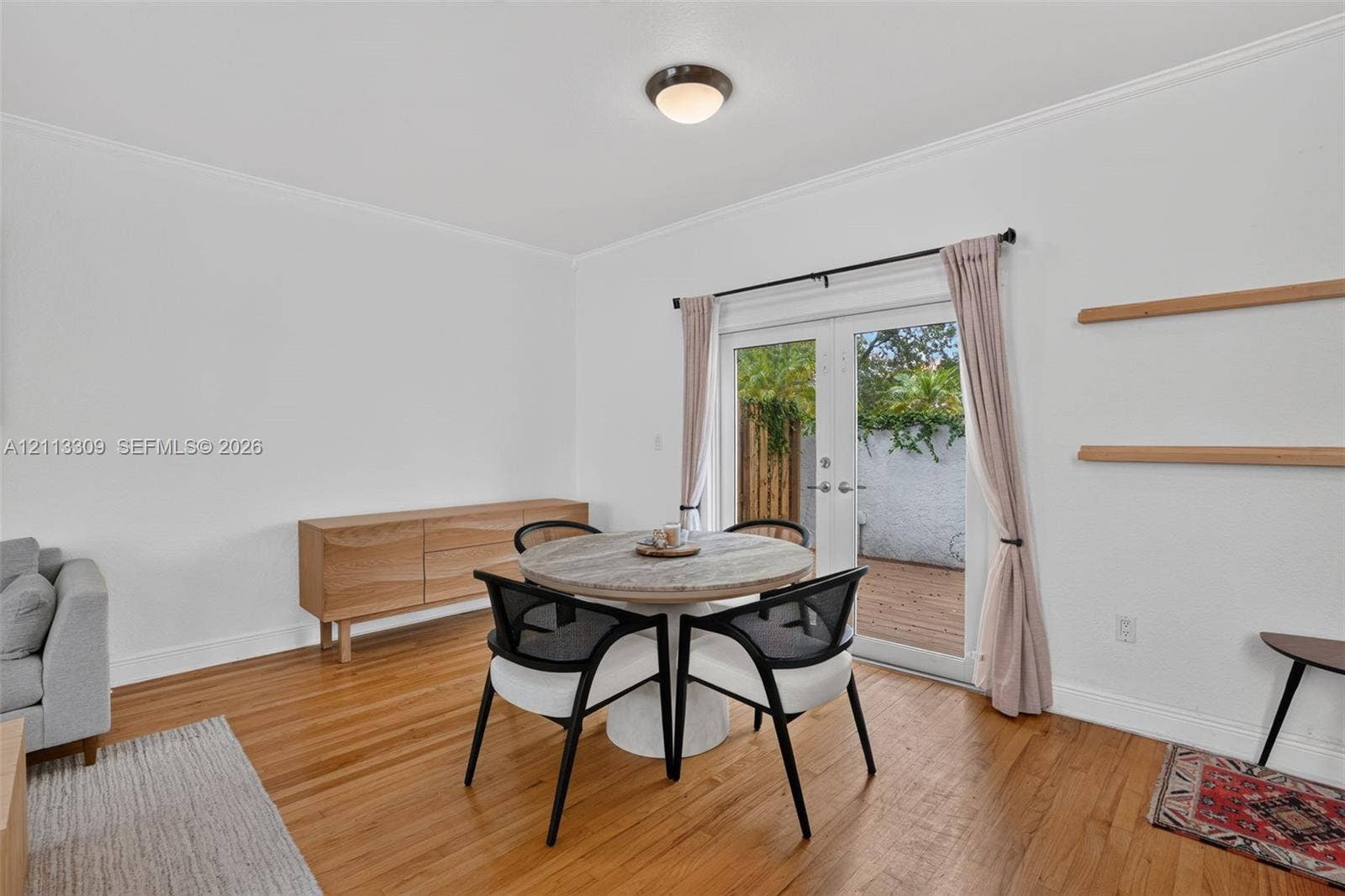 3082 Bird Avenue, #6, Miami, FL 33133 Wood-finish flooring, white walls, dual glass-paneled doors with exterior access, and dual built-in wall-mounted shelves