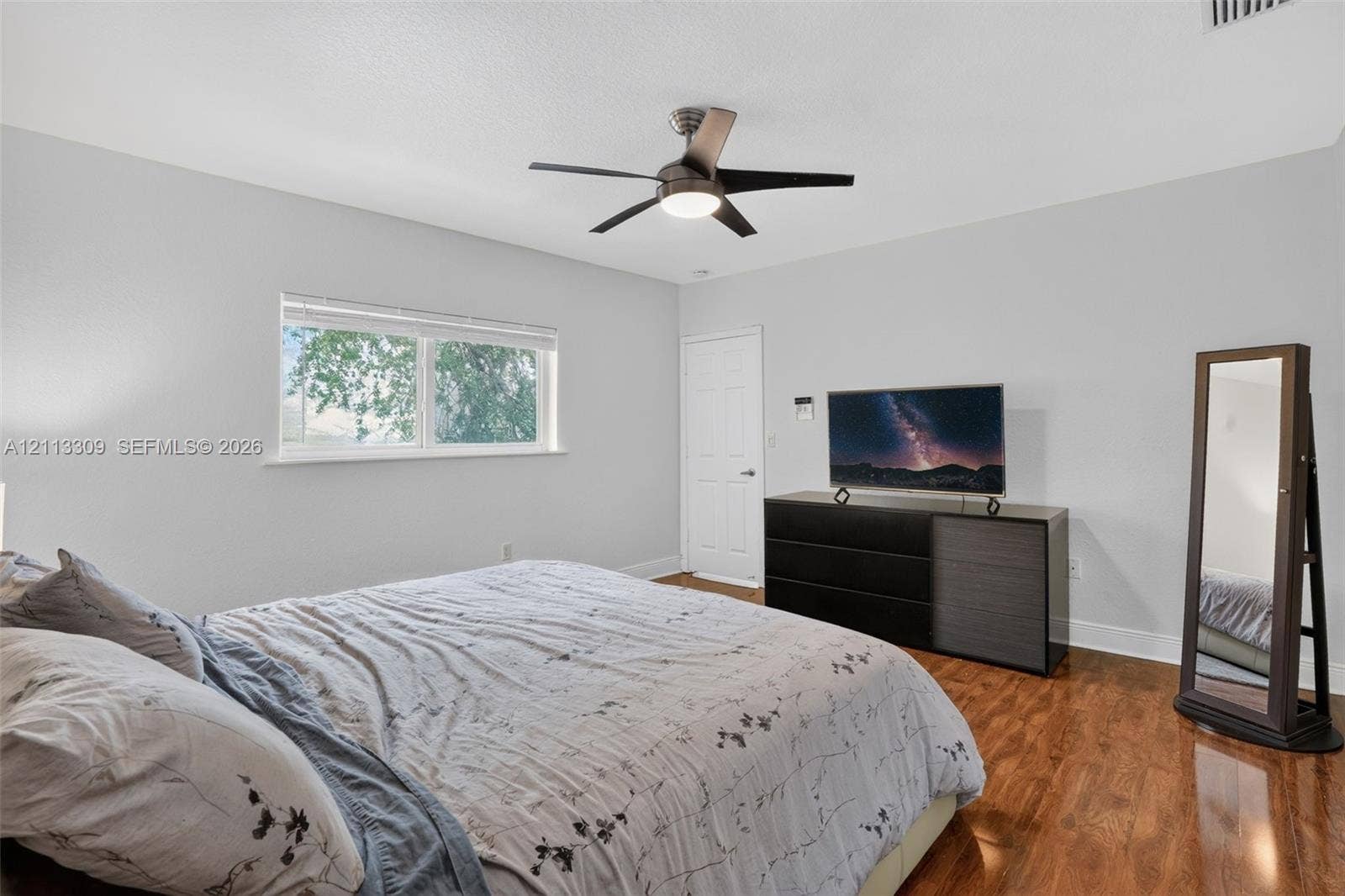 3082 Bird Avenue, #6, Miami, FL 33133 Wood-finish flooring, neutral wall tones, multi-blade ceiling fan with integrated lighting, and a window with horizontal blinds