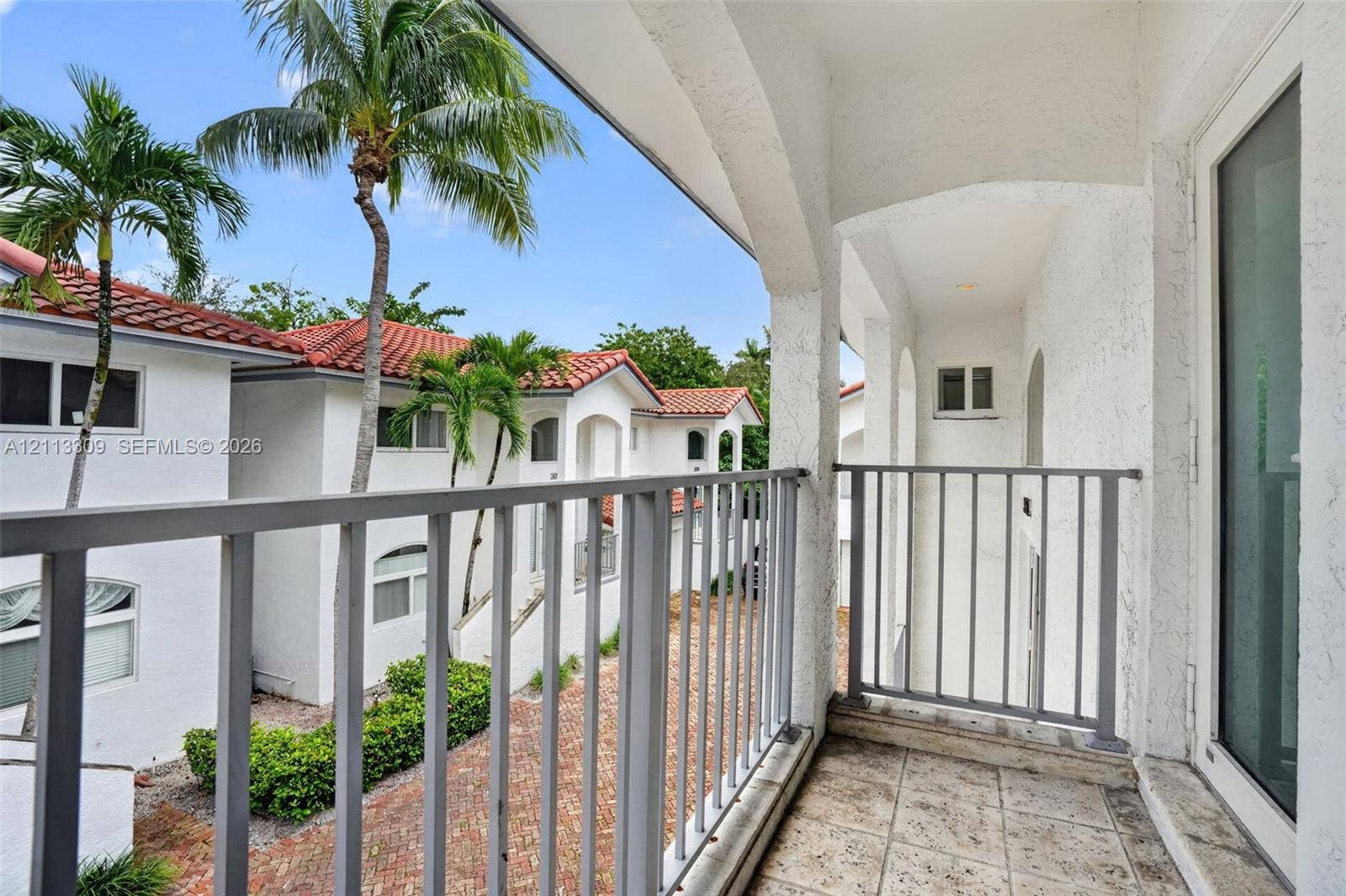 3082 Bird Avenue, #6, Miami, FL 33133 Covered balcony featuring stone tile flooring, stucco archways, and metal railings