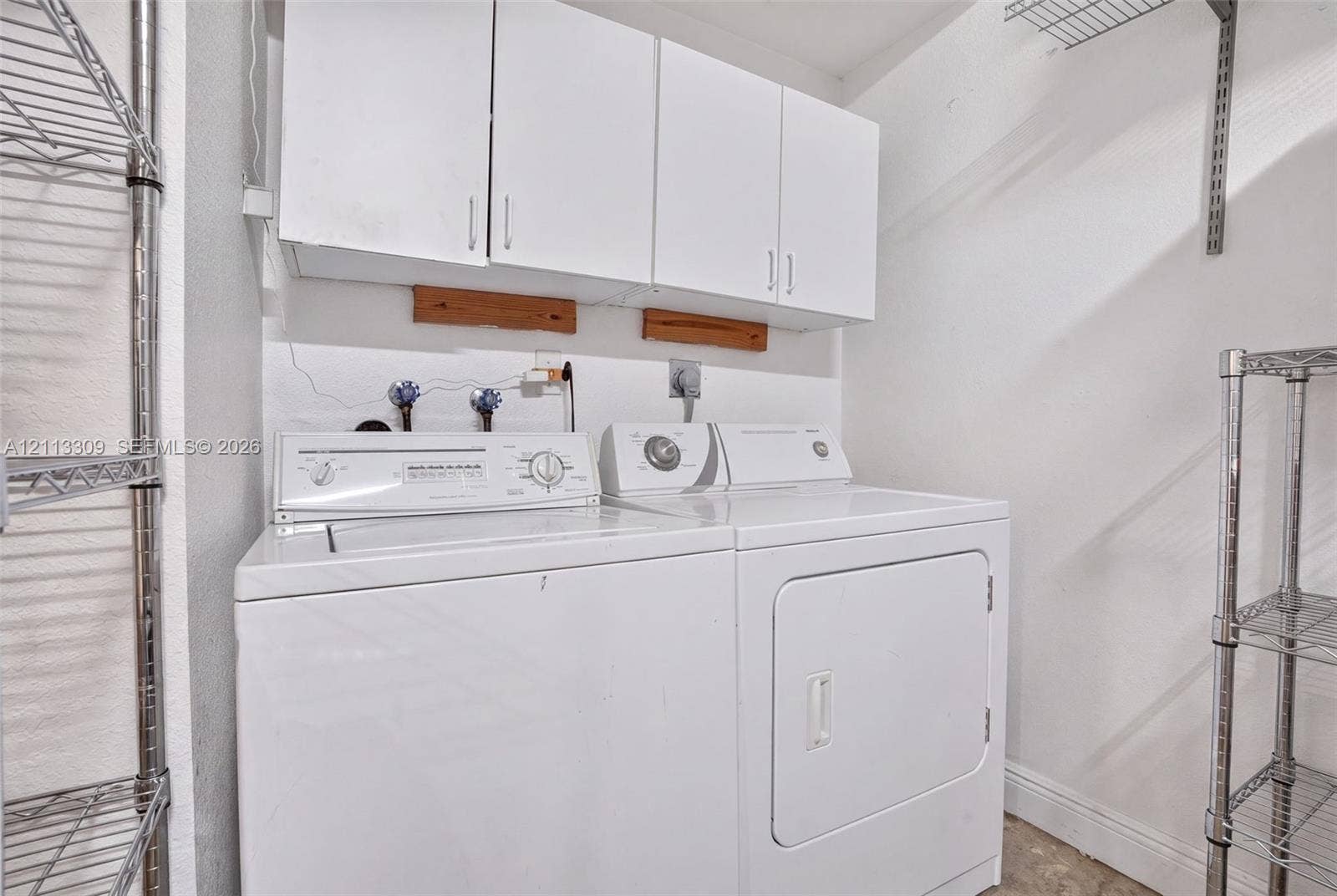 3082 Bird Avenue, #6, Miami, FL 33133 Laundry area featuring wall-mounted white cabinetry and adjustable metal shelving units